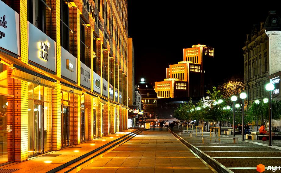 Зовнішній вигляд житлового комплексу Cascade Plaza з освітленими фасадами та прибудинковою територією з зеленими насадженнями.