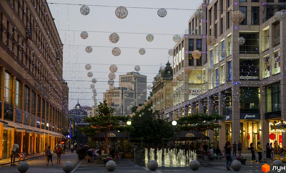 Житловий комплекс Cascade Plaza з сучасним фасадом та прибудинковою територією, прикрашеною світловими елементами.