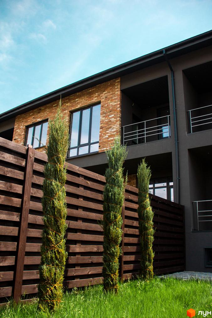 Таунхауси „Пушкінський“: цегляний фасад та зелені насадження біля будинку. Зовнішній вигляд новобудови та прибудинкової території.