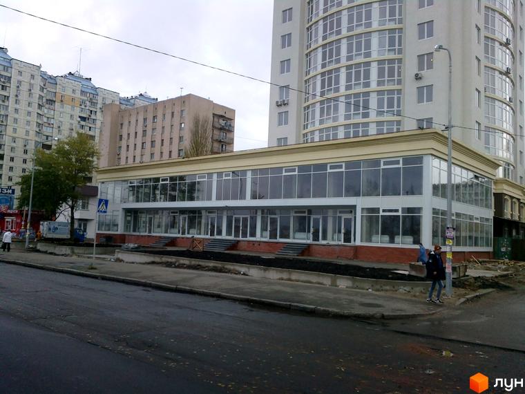 Зовнішній вигляд Житлового комплексу Оболонь Тауер. Висотна будівля з великими вікнами, прибудинкова територія з тротуарами та дорогою.