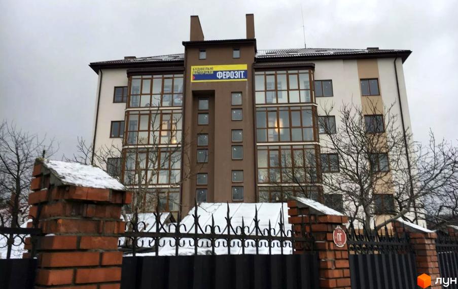 Будівельний проєкт на вул. Варшавська, 112. Багатоповерховий будинок з великими вікнами та балконами, огороджений парканом.