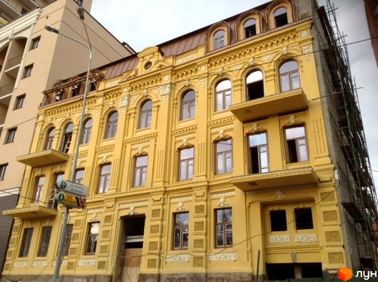 Зображення фасаду будинку Житлового комплексу Златоустівська 14-18. Будівля жовтого кольору з великими вікнами та декоративними елементами.