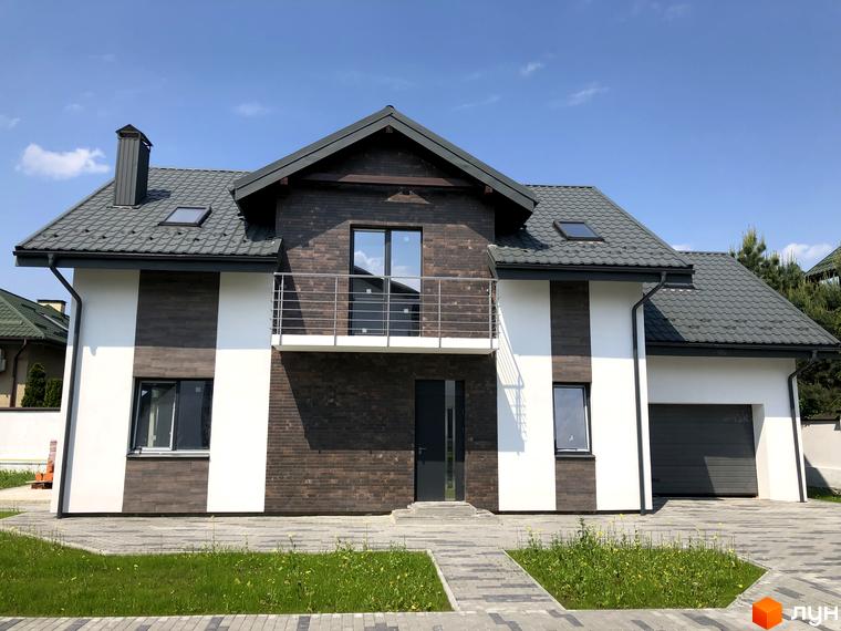 Зображення будинку в Котеджному містечку Європа. Двоповерховий будинок з балконом та сірим дахом, перед будинком газон.