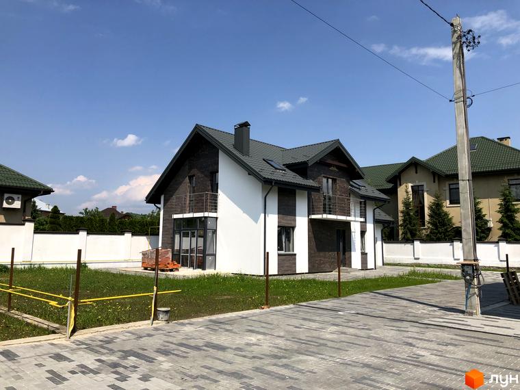 Зображення будинку в Котеджному містечку Європа з двома поверхами та балконами. Навколо будинку зелений газон та бруківка.