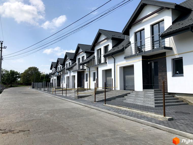 Зовнішній вигляд будинків Котеджного містечка Європа з балконами та гаражами. Близько розташована дорога з тротуарною плиткою.