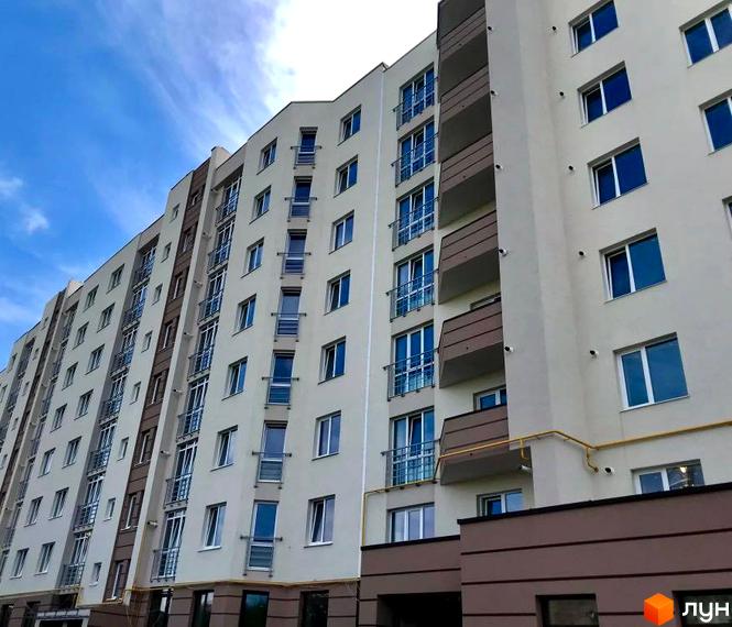 Багатоповерховий будинок ЖБ Липинський з світлим фасадом та коричневими вставками. Видно численні вікна та балкони з металевими поручнями.