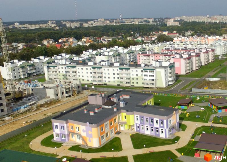 Житловий комплекс Академічний у Києві: сучасні багатоповерхові будинки з різнокольоровими фасадами та дитячий садок з яскравим дизайном. Територія комплексу озеленена.