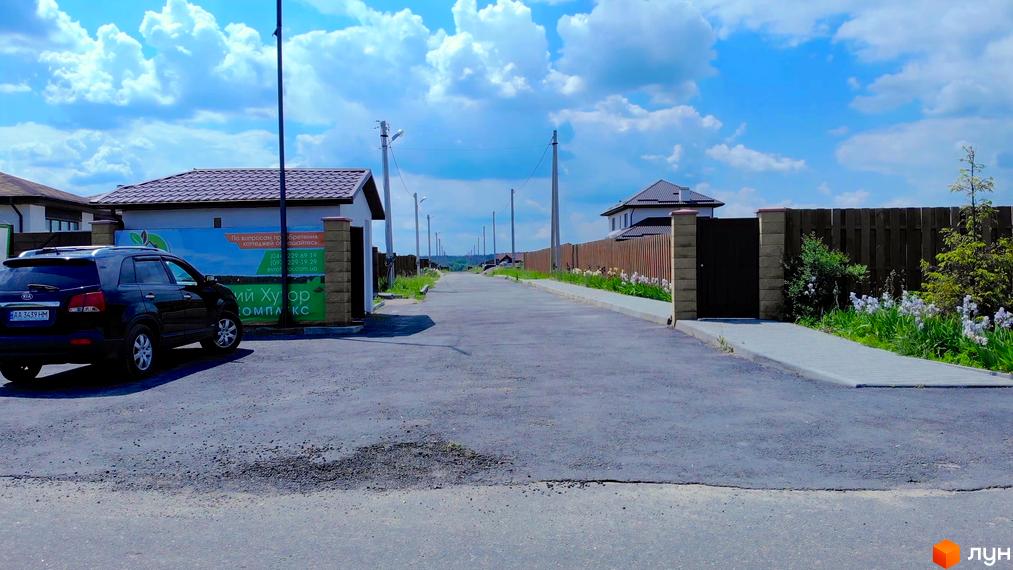 Котеджне містечко Михайлівський хутір: вулиця з будинками під коричневим дахом та парканом. Асфальтована дорога та тротуар.