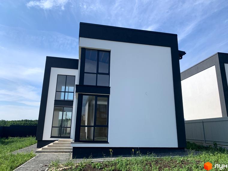 Котеджне містечко КМ Tivoli: двоповерховий будинок з білою та чорною обробкою, великими вікнами та доглянутою прибудинковою територією.