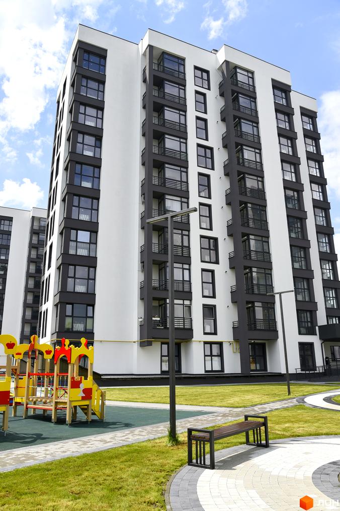 Новобудова ЖК Супернова з біло-сірими фасадами та балконами. Поруч дитячий майданчик, лавочка та доглянута зелена територія.