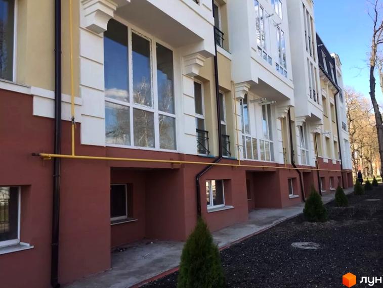 Будівельний проєкт на вул. Князя Чорного, 4а, з червоною цокольною частиною та білими фасадами, великими вікнами та зеленими насадженнями навколо.