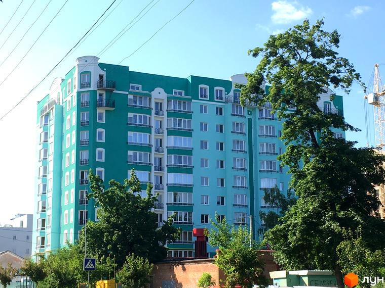 Будівельний проєкт Павленківська площа, 3б. Багатоповерховий будинок з блакитним фасадом та білими вікнами, оточений зеленню.