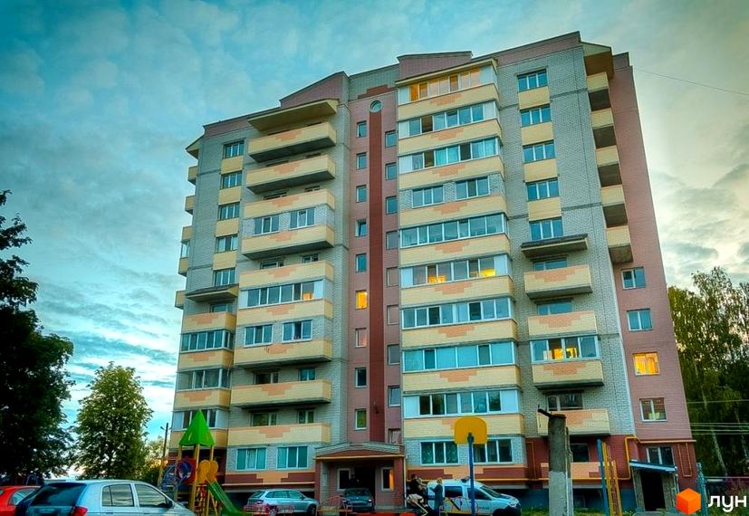 Багатоповерховий житловий комплекс на вулиці Вокзальна, 11а. Будинок має сіро-жовту облицювальну плитку та балкони. Біля будинку розташований дитячий майданчик та припарковані автомобілі.