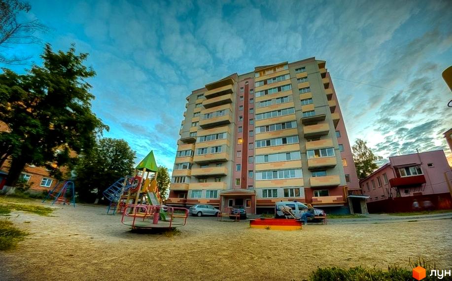 Зовнішній вигляд багатоповерхового будинку на вулиці Вокзальна, 11а. На прибудинковій території розташований дитячий майданчик з гірками та гойдалками.