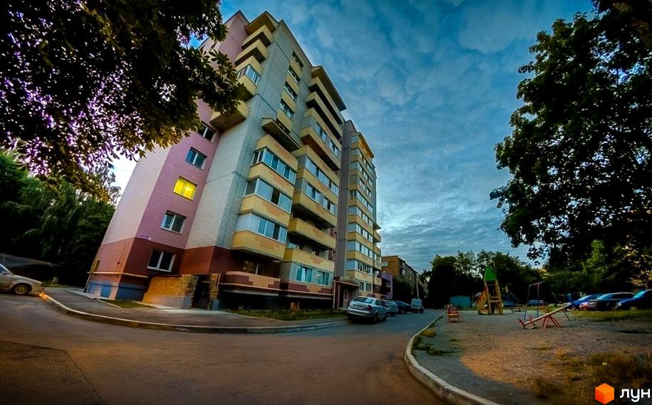 Зовнішній вигляд багатоповерхового будинку на вул. Вокзальна, 11а, з балконами та вікнами. Прибудинкова територія включає дитячий майданчик та припарковані автомобілі.