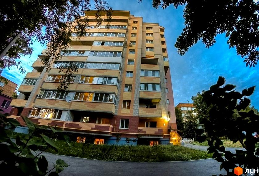 Зовнішній вигляд багатоповерхового будинку на вулиці Вокзальна, 11а. Навколо будинку зелена зона та дерева.