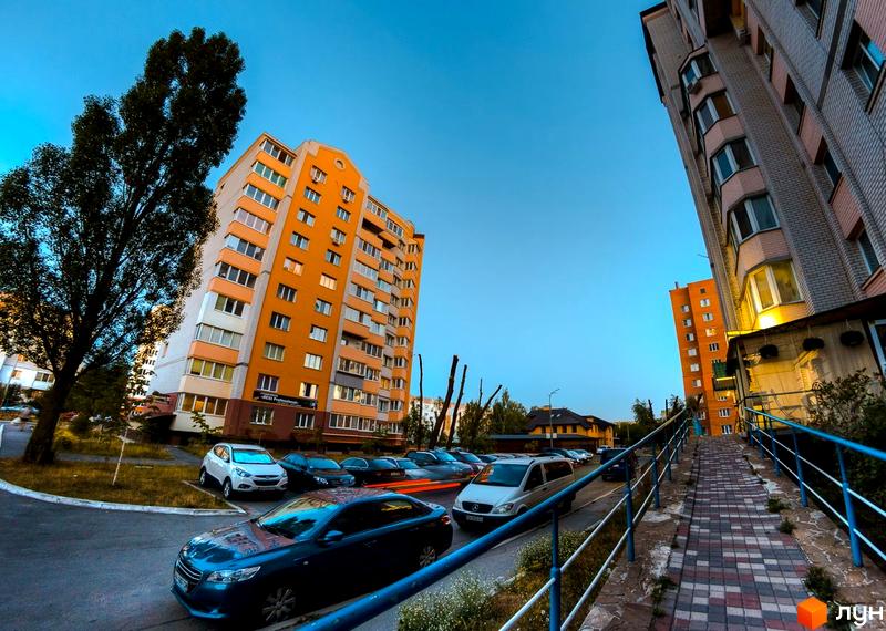 Житловий комплекс на вулиці Вокзальній, 49. Багатоповерхові будинки з оранжевими та сірими фасадами, прибудинкова територія з деревами та припаркованими автомобілями.