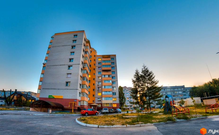 Житловий комплекс на вул. Вокзальна, 49. Сіра багатоповерхівка з оранжевими елементами та дитячим майданчиком біля будинку.