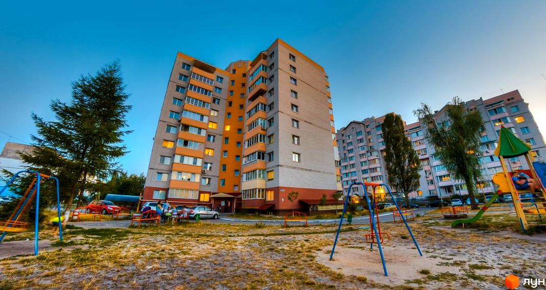 Зовнішній вигляд багатоповерхових будинків за адресою вул. Вокзальна, 49. Прибудинкова територія з дитячим майданчиком та деревами.