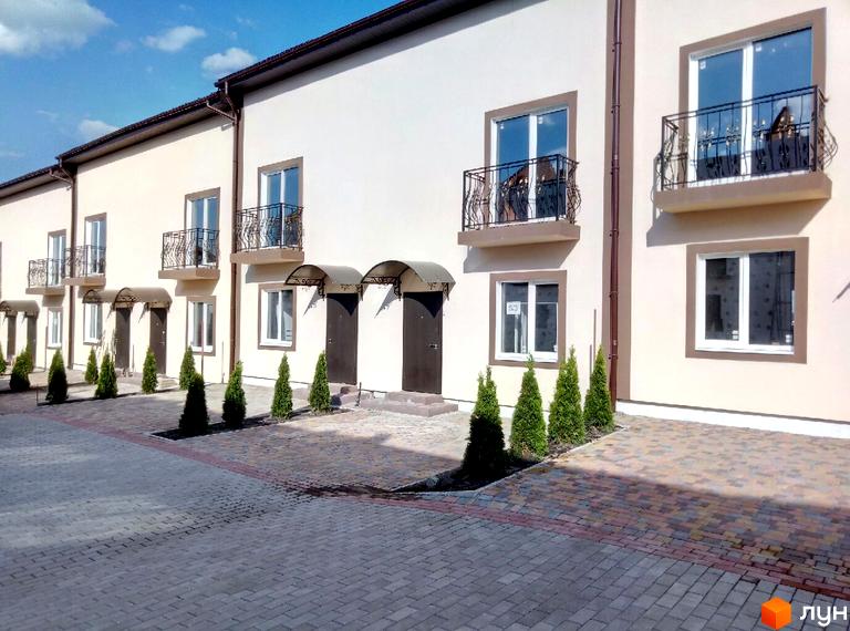Таунхауси Cherry Town. Зовнішній вигляд будинків з балконами та вікнами. Прибудинкова територія з бруківкою та туями.