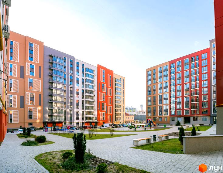 Яскравий житловий комплекс Семицвіт з різнокольоровими фасадами. На території комплексу є зелені зони, лавки та дитячий майданчик.