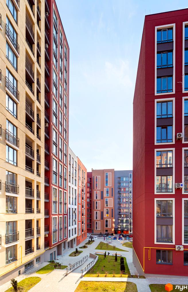 Житловий комплекс Семицвіт. Високі будинки з великими вікнами та балконами. Доглянута прибудинкова територія з газонами та тротуарами.