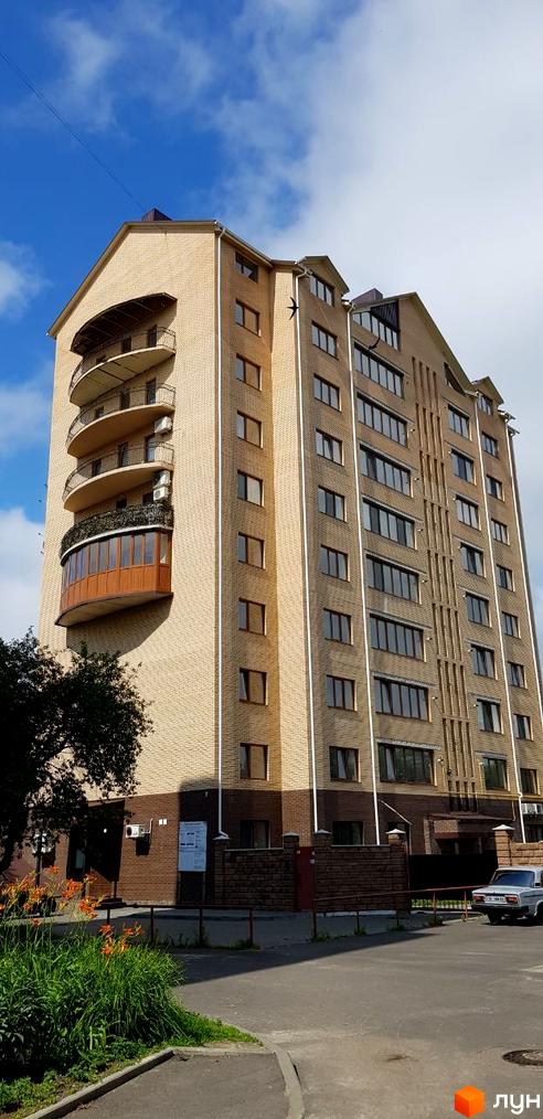 Будівельний проєкт просп. Соборності, 16в. Багатоповерховий будинок з цегляним фасадом та балконами. Навколо будинку зелена зона та доглянута прибудинкова територія.