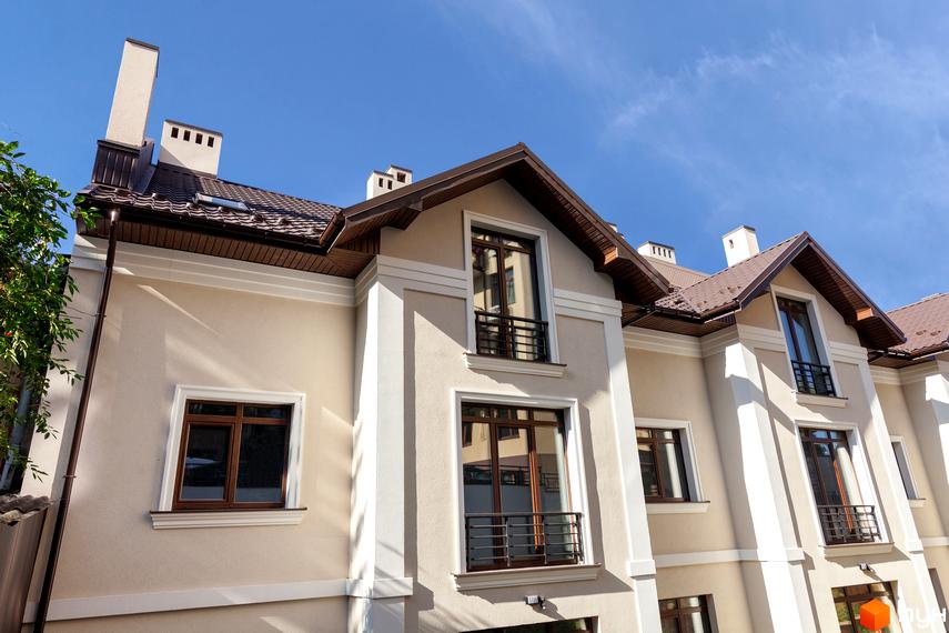 Таунхауси „Вілли на Личаківській“ – фасади будинків з коричневим дахом та великими вікнами. Зовнішній вигляд новобудови під блакитним небом.