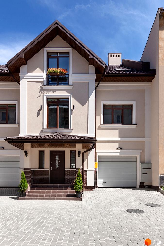 Таунхауси „Вілли на Личаківській“ з бежевим фасадом та темним дахом. Перед будинком вимощена територія та два гаражі.