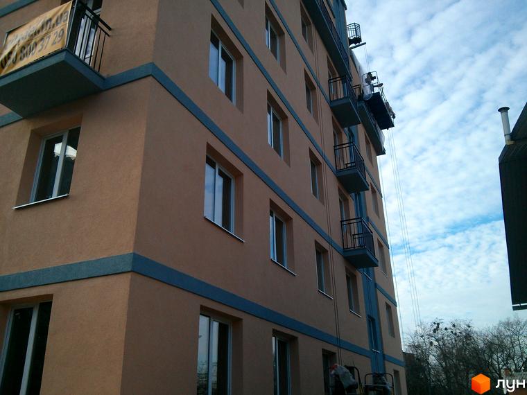 Клубний будинок „Цитадель“ з цегляним фасадом та балконами. На фасаді видно вікна та декоративні елементи. Навколо будинку видно дерева та хмарне небо.