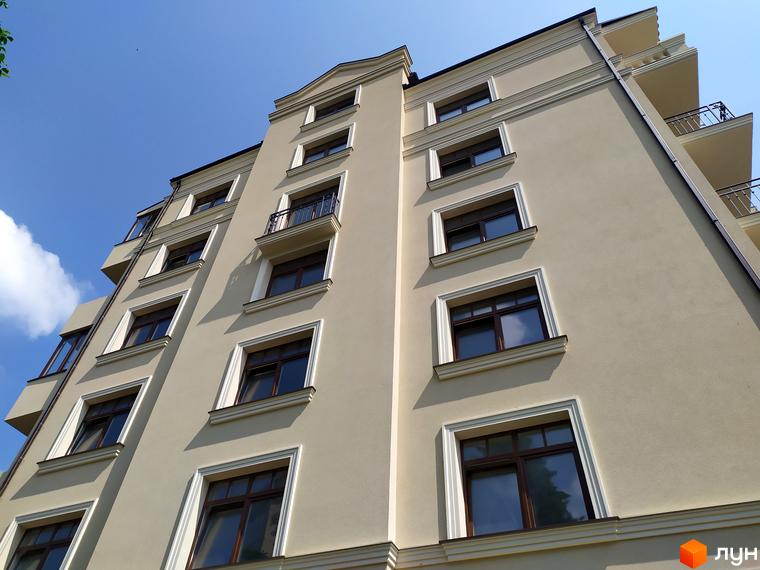 Житловий комплекс Версаль з великою кількістю вікон та балконами. Будинок виконаний у світлих тонах на фоні блакитного неба.