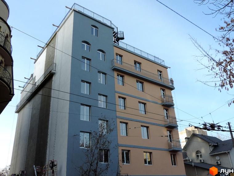 Клубний будинок „Цитадель“ - цегляний будинок з сірими та бежевими фасадами, з балконами та великими вікнами. Навколо будинку видно дерева та дроти.