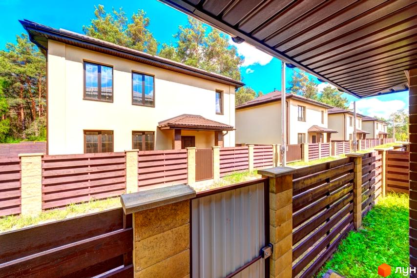 Котеджне містечко Garmonia: бежеві двоповерхові будинки з коричневими дахами. Перед будинками дерев'яні огорожі та зелений газон.