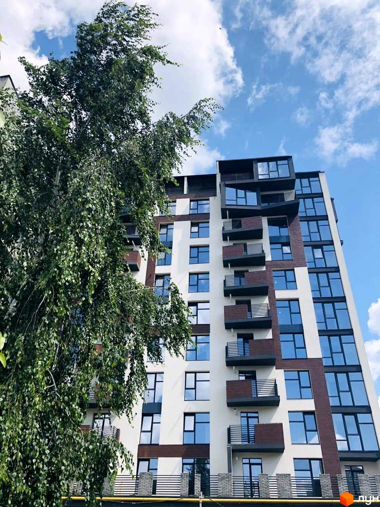 Новобудова ЖК Перлина Проскурова з великими вікнами та балконами. Зелені дерева перед фасадом будівлі.