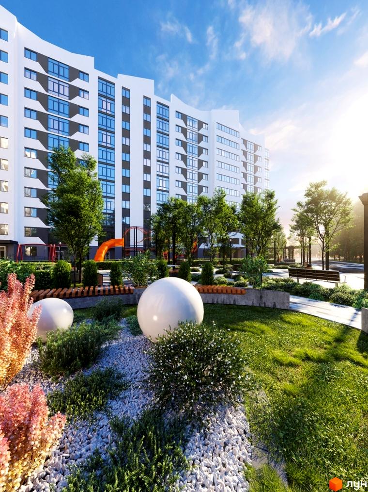 Житловий комплекс Авіатор: біла багатоповерхова будівля з синіми вікнами та зелена прибудинкова територія з дитячим майданчиком.