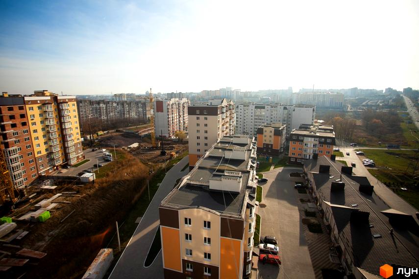 Житловий комплекс Срібні Озера Комфорт. Зовнішній вигляд будівель та прибудинкова територія з дорогою та автомобілями.