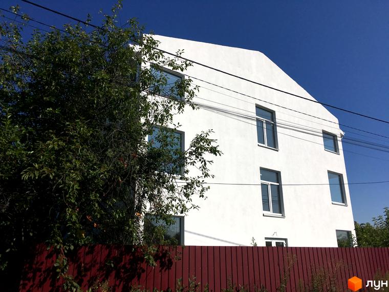 Клубний будинок „Женева“: білий триповерховий будинок з прямокутними вікнами під синім небом. Перед ним видно червоний паркан та велике зелене дерево.