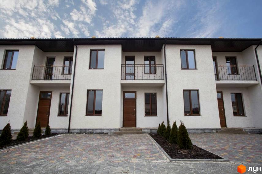 Зовнішній вигляд будинку на вулиці Одеській, 4. Фасад білого кольору з коричневими вікнами та дверима, перед будинком викладена плитка.