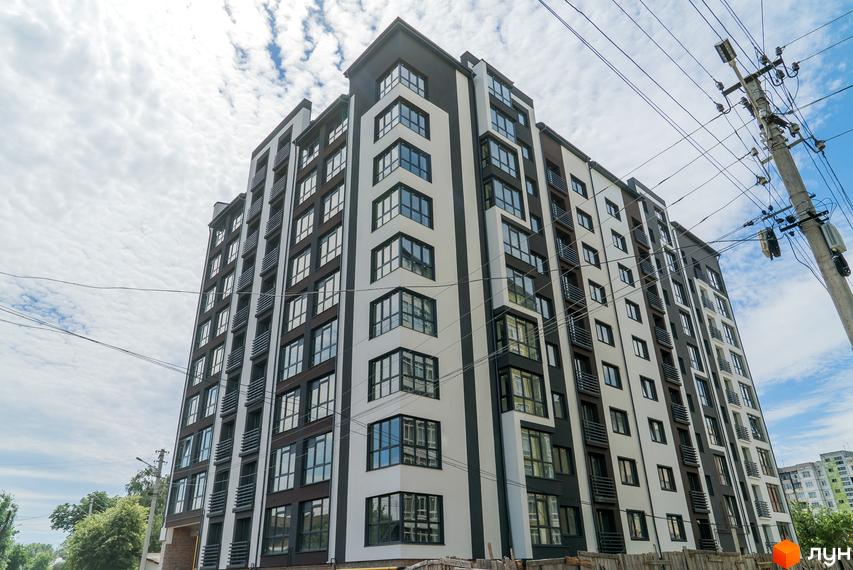 Висотна Новобудова Franko Smart House з панорамними вікнами на тлі хмарного неба. Фасад будинку виконаний у білих та темно-сірих тонах, з балконами.