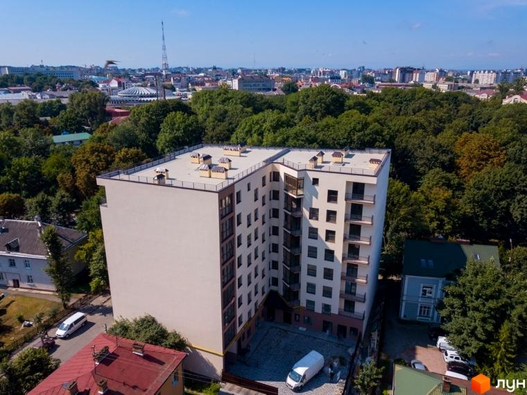 Зовнішній вигляд ЖК Central House з багатьма вікнами та балконами, а також прибудинкова територія з парковкою та зеленими насадженнями.
