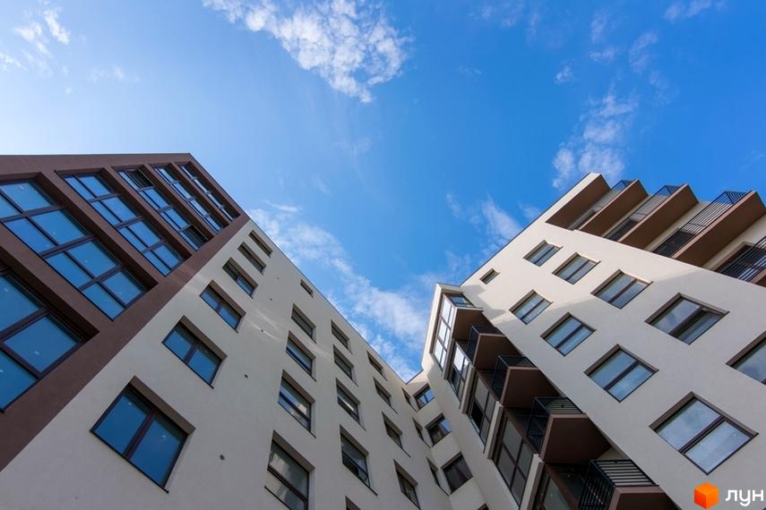 Житловий комплекс Central House - фасади будівель з великою кількістю вікон та балконів на фоні блакитного неба з хмарами.