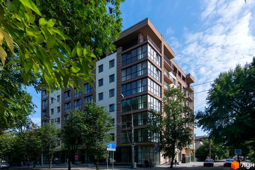 Зовнішній вигляд новобудови ЖК Central House з великою кількістю вікон та балконів, оточеної деревами. Навколо будинку облаштована прибудинкова територія з тротуаром та дорогою.