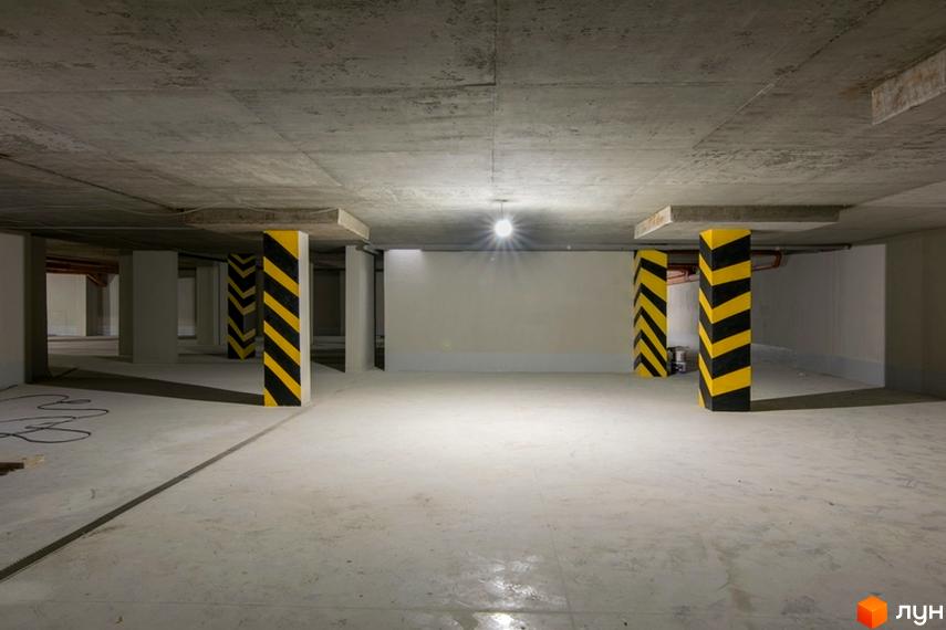 Паркінг у новобудові ЖК Central House з бетонною стелею та колонами, позначеними жовто-чорними смугами.
