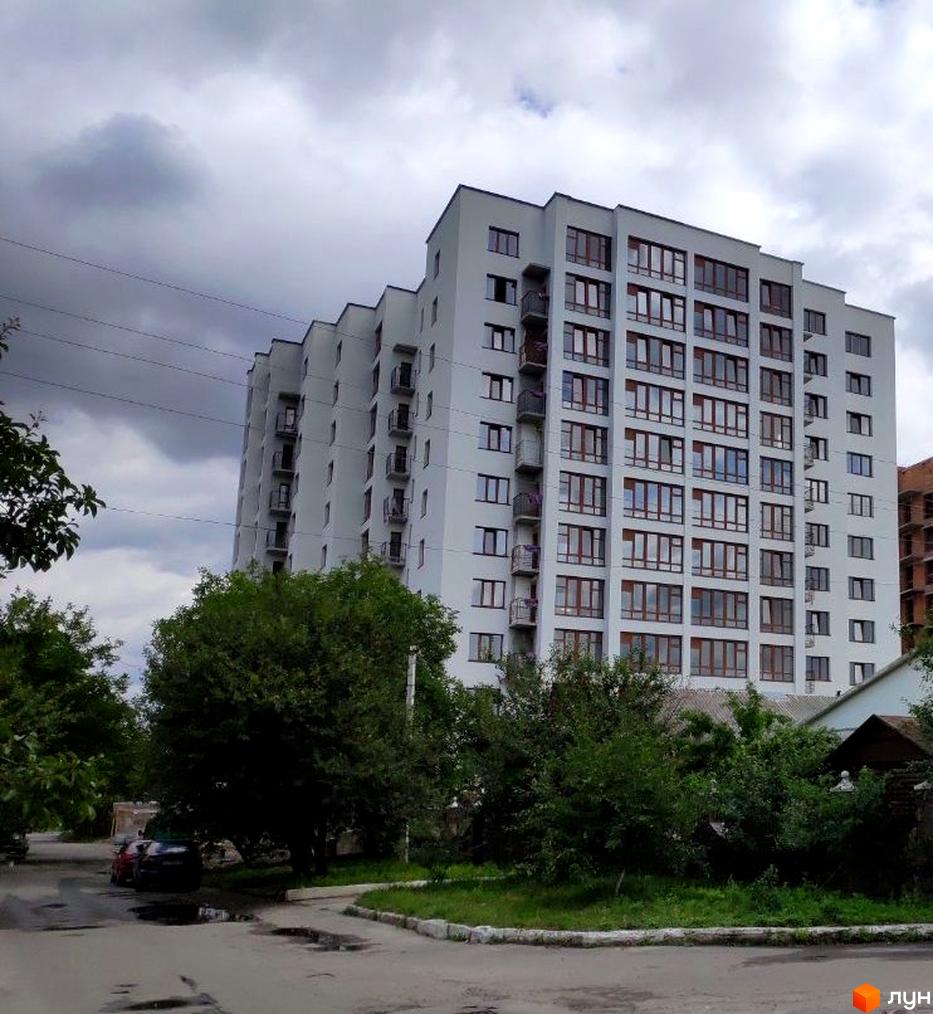 Зображення багатоповерхового будинку на вулиці Плоска, 23/1. Навколо будинку зелені насадження та дорога.