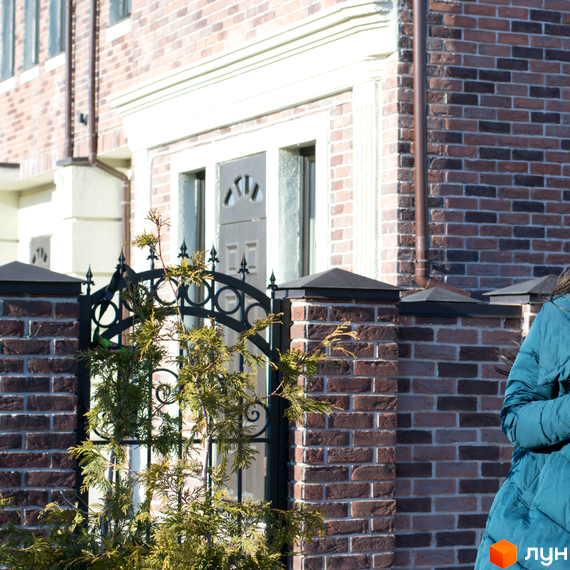 Таунхауси Liverpool House з цегляним фасадом та кованими елементами біля входу. Навколо зелені насадження та паркан.