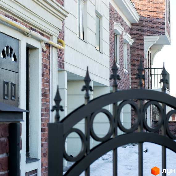 Таунхауси Liverpool House з цегляним фасадом та білими декоративними елементами. Перед будинком ковані ворота та засніжена територія.