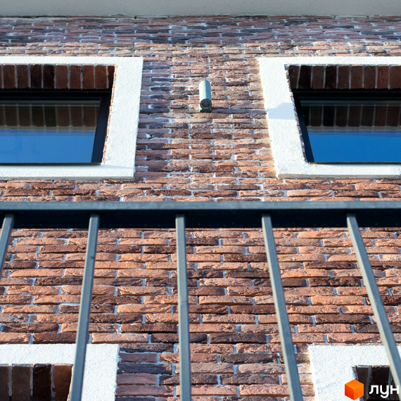 Фасад таунхаусів Liverpool House з цегляною кладкою та вікнами. Огорожа з металевими прутами на передньому плані.