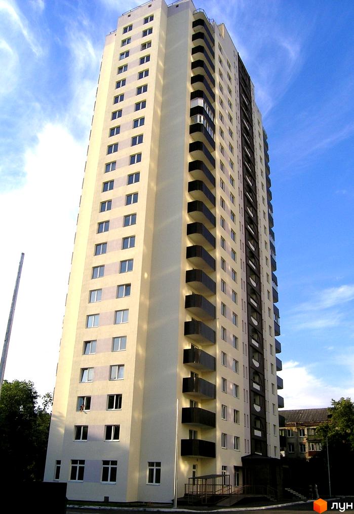 Висотна новобудова з великою кількістю вікон та балконів. На території є зелені насадження та будівлі.