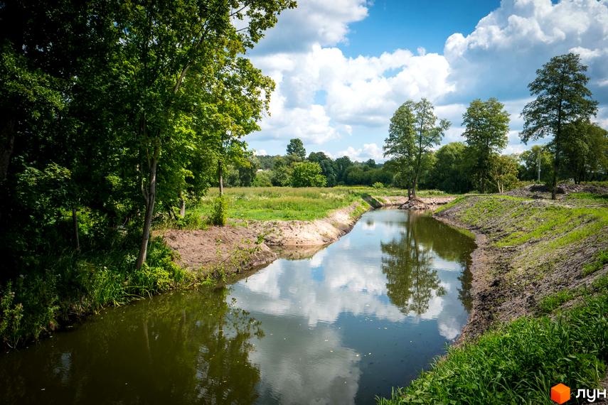 Зображення річки поруч з Котеджним містечком Sun City. Навколо зелені дерева та трава, що створює природний ландшафт.