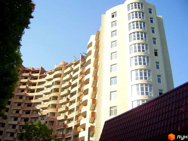 Житловий комплекс Каскад з сучасною архітектурою та просторими балконами. Прибудинкова територія озеленена деревами та кущами.